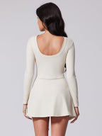 Woman wearing a white dress with long sleeves on a plain background